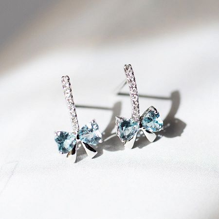 Wholesale Dainty 925 Sterling Silver Cubic Zirconia Blue Bowknot Stud Earrings (5 Sets) - A pair of dainty 925 sterling silver bowknot stud earrings, each featuring a central light blue cubic zirconia gemstone and accented with clear crystals.