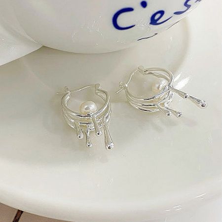 An alternative angle of the silver pearl drop earrings, displaying the intricate, flowing metalwork.