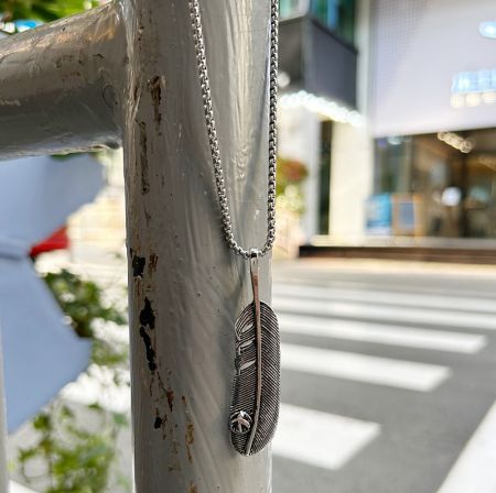 Feather pendant necklace worn in an urban setting to showcase its style.