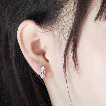 Detailed shot of a single silver camellia earring, emphasizing the craftsmanship and sparkling stones.