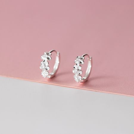 Detailed view of the silver floral hoop earrings showcasing the clear gemstone accents.