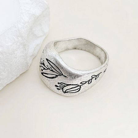 Close-up view of the silver ring's intricate floral engraving.