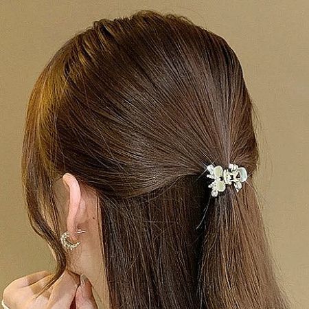 A woman showcasing a stylish half-up hairstyle secured with a decorative floral hair clip.