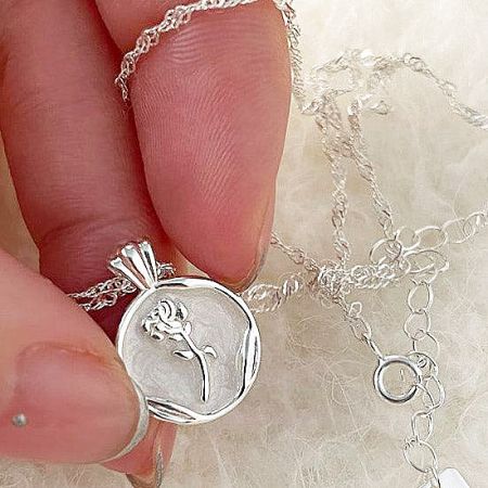 Close-up of the intricate texture and design of the silver floral pendant.