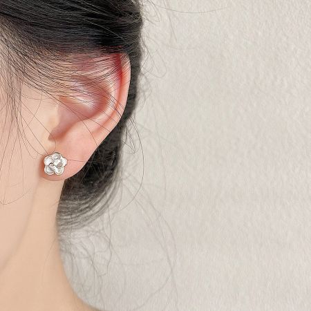 A model wearing the delicate white and gold enamel flower stud earring.