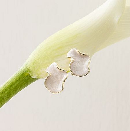 A pair of the abstract white and gold earrings displayed creatively on a white flower bud.