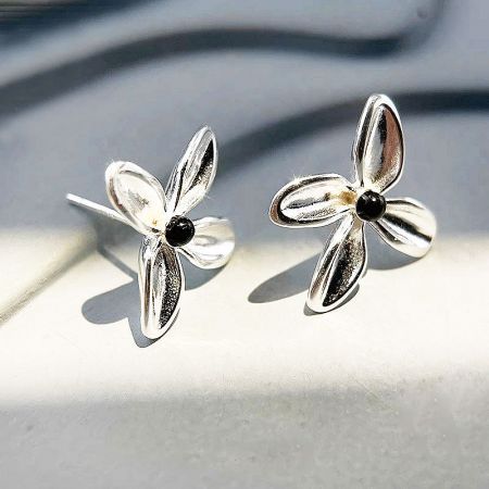 Orecchini a bottone a forma di fiore in onice nero semplice in argento sterling 925 (5 paia) - Un primo piano di un paio di orecchini a bottone a forma di fiore in argento sterling 925 con centri in onice nero lucido, su uno sfondo bianco pulito.