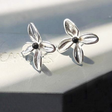Detailed view of the sterling silver flower stud earrings with four petals and a black onyx center.