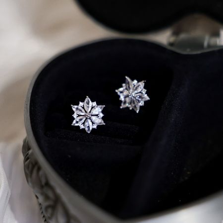 Silver flower earrings elegantly presented in a heart-shaped gift box.