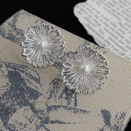 Close-up view of a pearl center statement floral earring, highlighting the textured petal details.