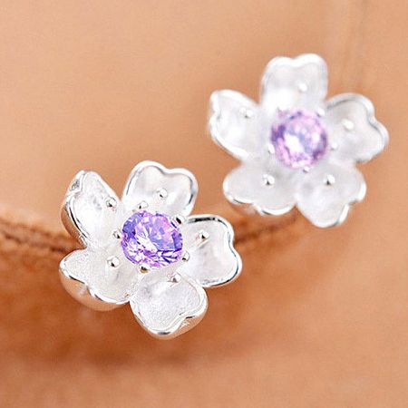 Promotional shot of the pair of silver flower earrings with purple gemstones.