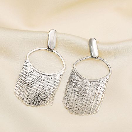 A pair of silver fringed earrings displayed on a neutral surface.