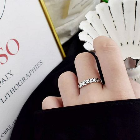 Product shot of a silver ring with a modern geometric pattern.