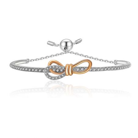 Tied Ribbon Bow Bangle - A close-up of the Tied Ribbon Bow Bangle, featuring a two-tone rhodium and rose gold finish with sparkling white cubic zirconia stones.