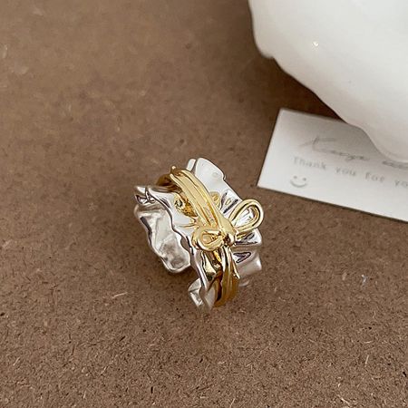 A stylish two-tone adjustable bow ring in gold and silver, displayed on a neutral background.