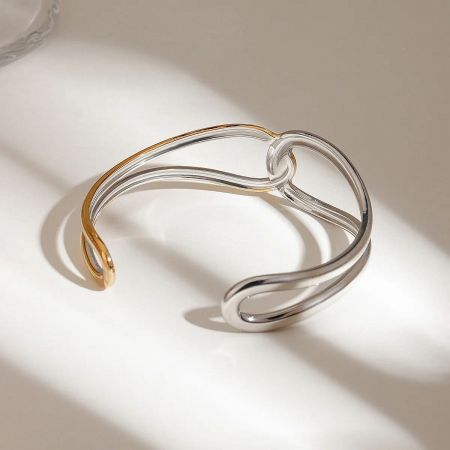 A bold two-tone gold and silver open cuff bracelet made from waterproof stainless steel.