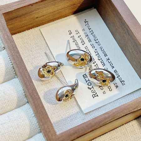 Close-up of the two-tone stud earrings with black stones in a wooden box.