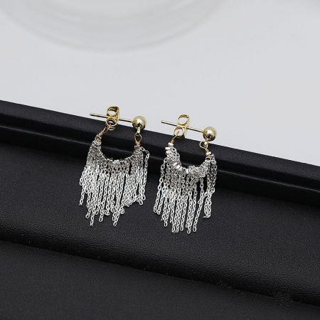 Another angle of the silver and gold tassel earrings against a white background.