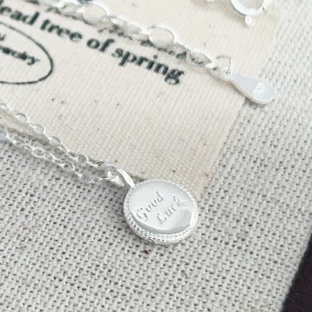 Another angle of the 'Good Luck' silver necklace, showing the chain and clasp.