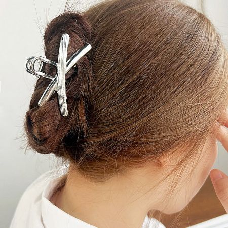 A model showcasing the silver cross-hair claw clip securing a neat hair bun.