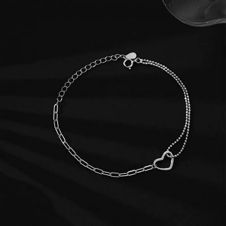 Close-up view of the minimalist sterling silver heart charm bracelet with its adjustable clasp.