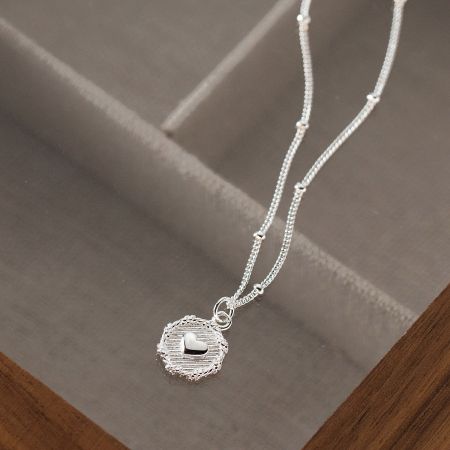 Detailed shot of the silver heart pendant, highlighting its smooth, reflective surface.