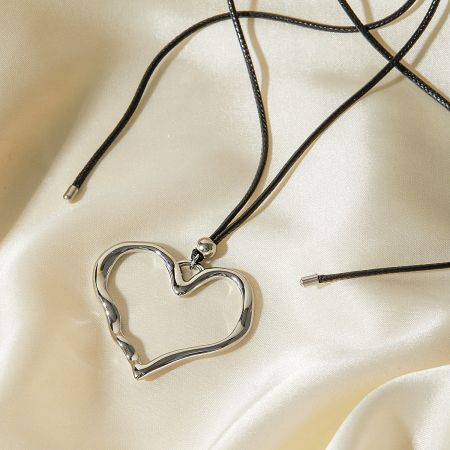 The silver heart pendant displayed on a luxurious cream satin fabric.