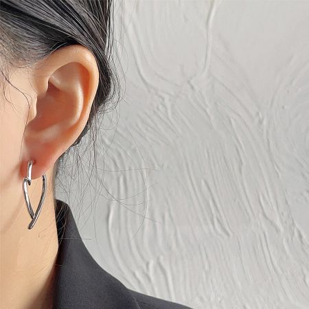 Model wearing the minimalist silver heart-shaped stud earring to show scale and style.