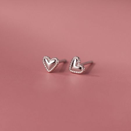 Close-up view of a silver heart-shaped stud earring with a textured border.