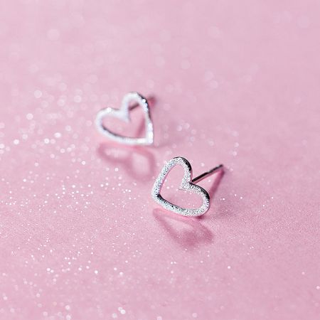 Close-up view of the sterling silver hollow heart stud earrings.