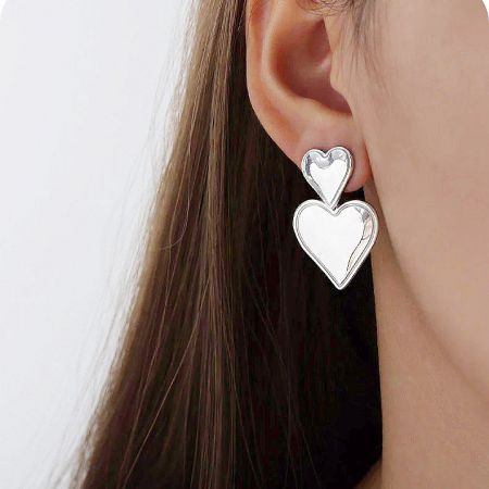 Model showcasing the elegant silver stainless steel double heart drop earrings.
