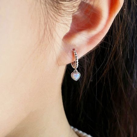 Model wearing the 925 sterling silver heart opal huggie earring.