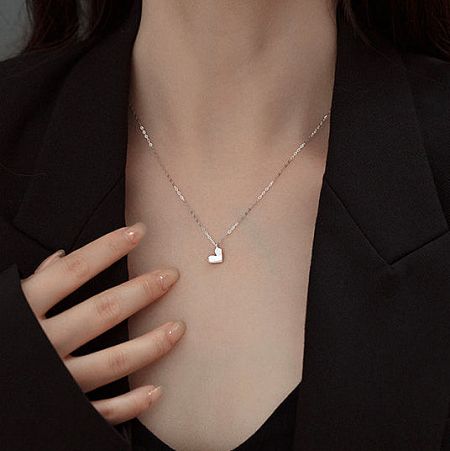 Detailed view of the silver heart necklace on a model.