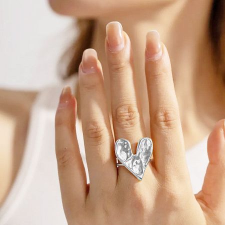 A woman's hand wearing the adjustable stainless steel heart ring on the middle finger.