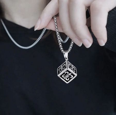 A silver necklace with a unique hexagonal pendant featuring floral designs on each face, another variation of the men's necklace.