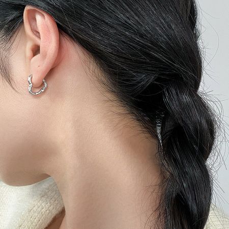 Model showcasing the elegant fit of the minimalist silver heart hoop earrings.