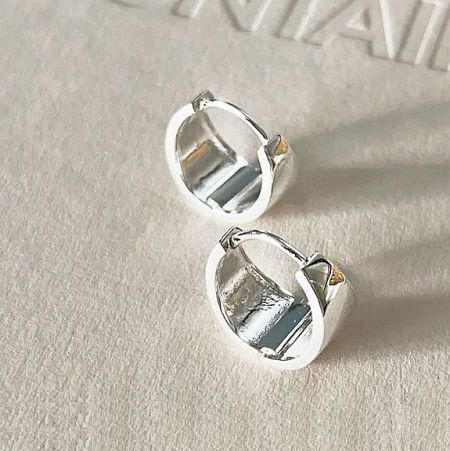 A pair of 925 sterling silver wide hoop earrings on a neutral background.