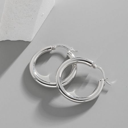 A pair of 925 sterling silver small thick hoop earrings with a polished silver finish, presented on a white display stand.