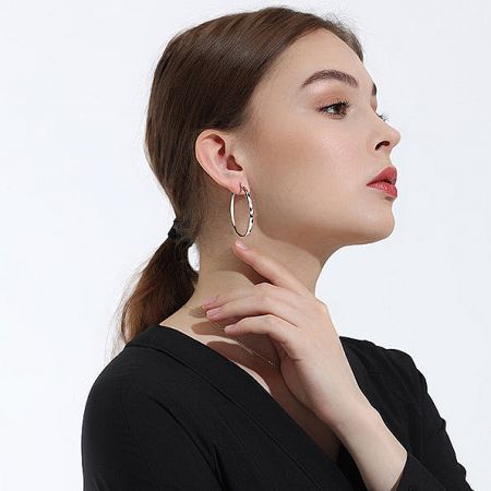 Detailed view of the sterling silver hoop earrings, highlighting the intricate diamond-texture pattern.