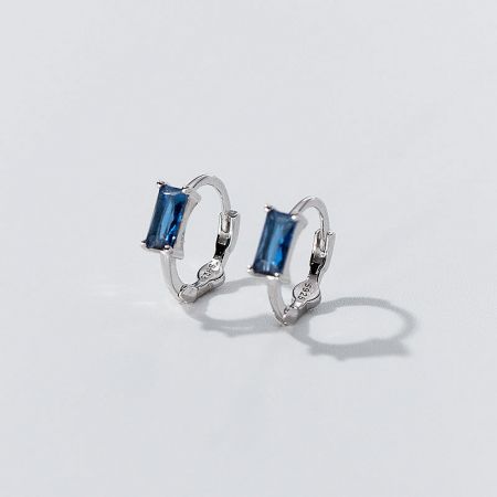 A pair of elegant silver hoop earrings featuring vibrant blue gemstones.