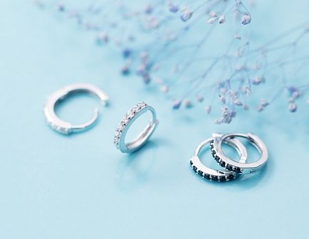 A display of silver hoop earrings featuring both clear and black cubic zirconia stones.