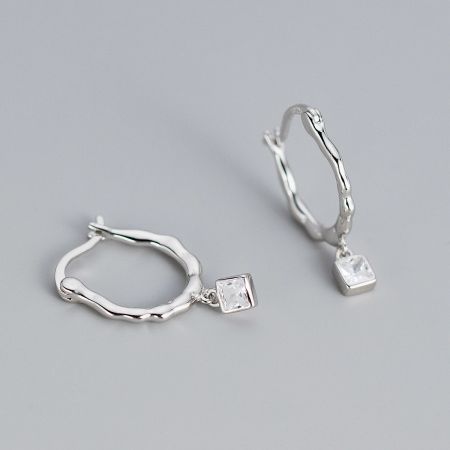 A pair of silver twisted hoop earrings with clear square-cut gemstones on a white background.