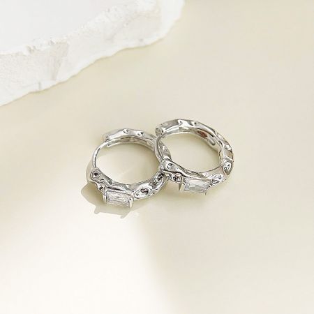 A pair of silver hammered huggie hoop earrings with sparkling zircon stones.