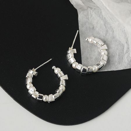Another perspective of the silver hoop earring, emphasizing the texture of the cube-shaped beads.