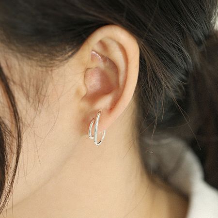 The silver version of the double C hoop stud earrings worn on an ear, showing its versatile and chic style.