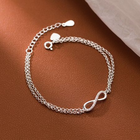 Detailed view of the infinity bracelet on a leather surface, highlighting the crystal accents.