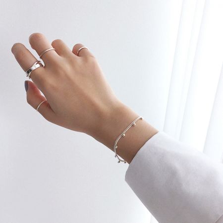 Multiple minimalist sterling silver rings worn on a model's hand, demonstrating a stylish stacked look.