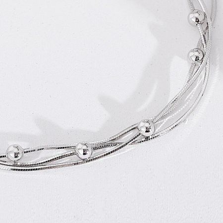 Artistic shot of the interwoven wires and decorative beads on the silver bracelet.