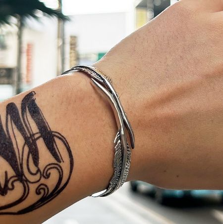 A man wearing the stainless steel feather bangle on his wrist, highlighting its fit and style.