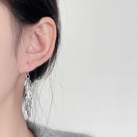 A model wearing the silver leaf-shaped dangling earring to showcase its size and style.